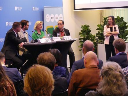 De sprekers zitten aan de tafel